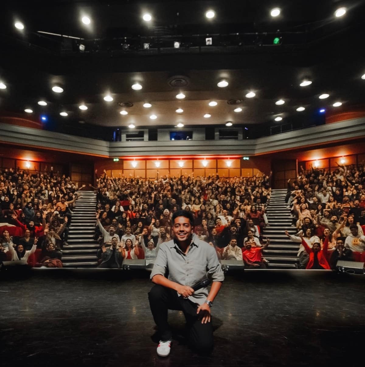 Aakash Gupta seated in front of a packed theatre audience